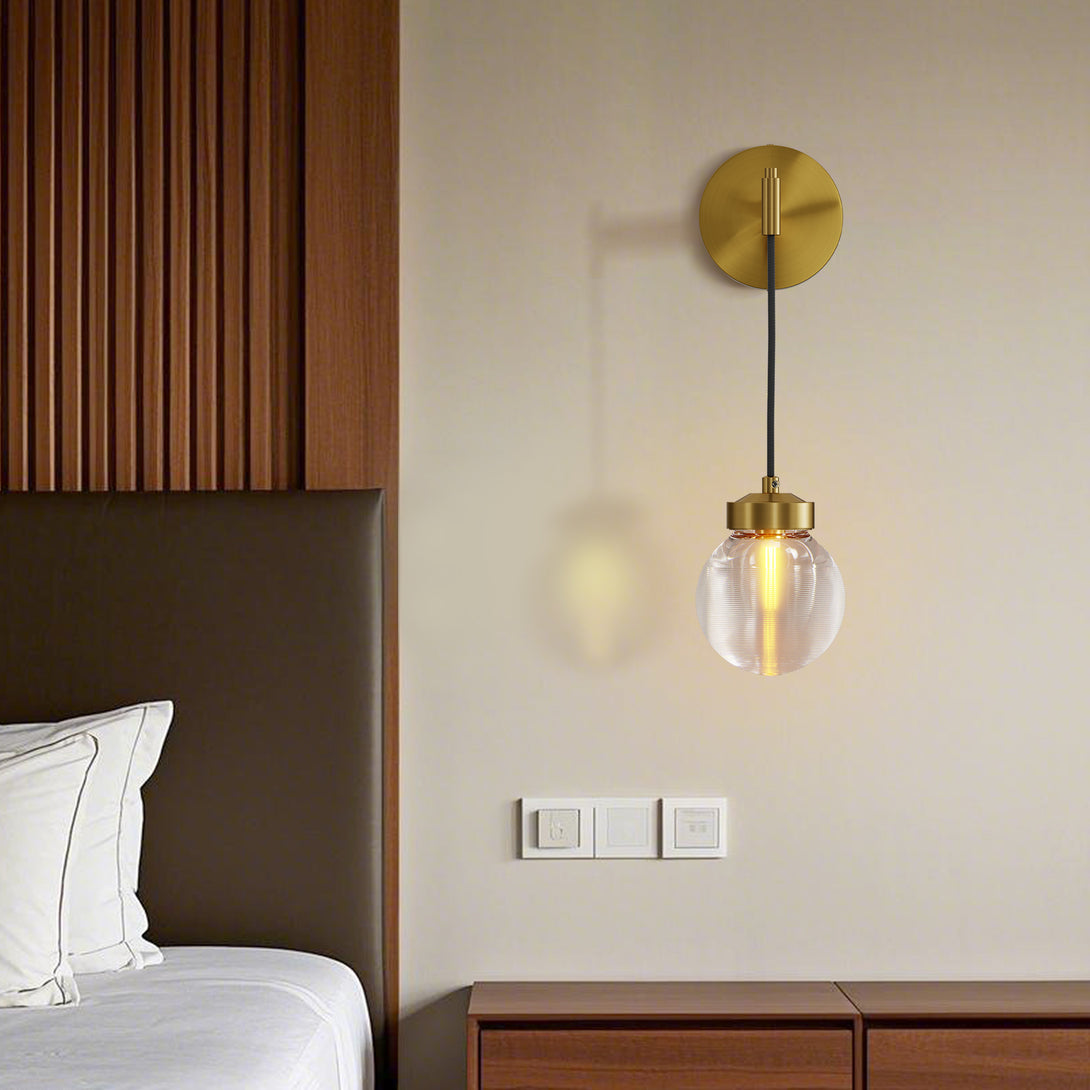 Copper globe wall sconce beside a bed showing its relationship to the mattress, pillow, nightstand, and seated reading position