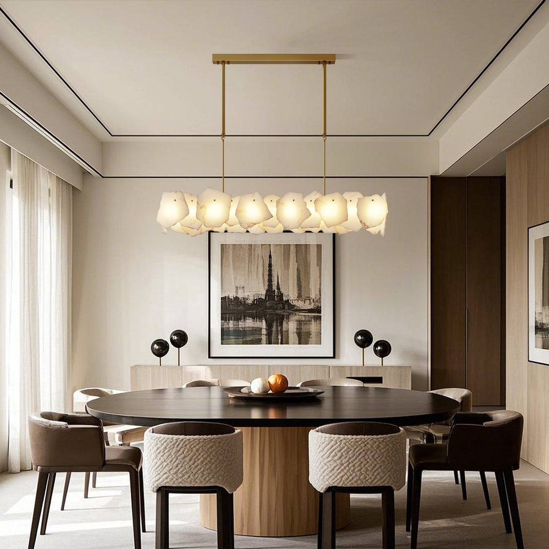 Linear chandelier with irregular pale panels above a round wood dining table in a neutral room
