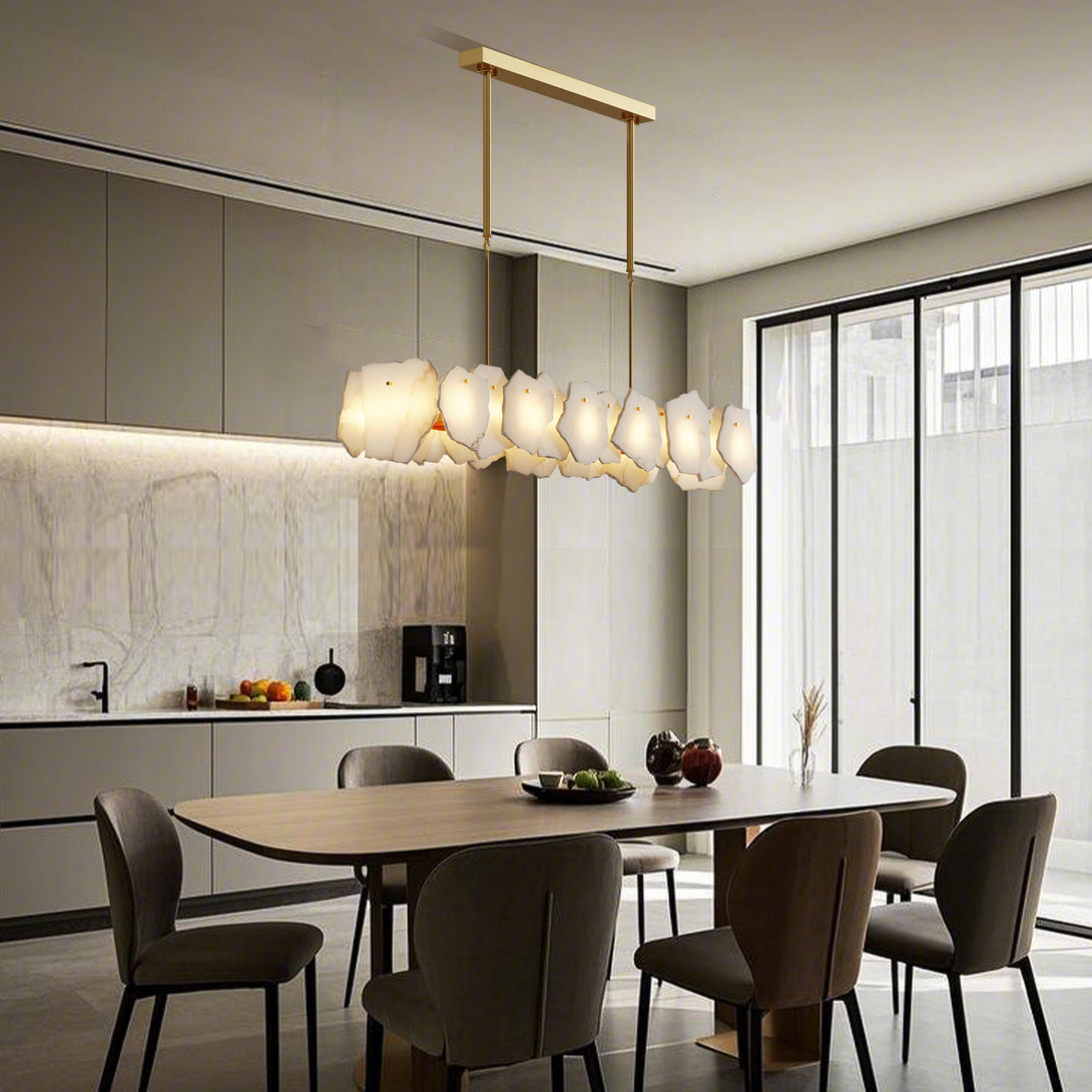 Illuminated linear chandelier with irregular pale panels above a rectangular dining table beside tall windows